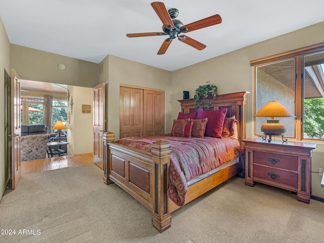 bedroom with light wood-type flooring, ceiling fan, and a closet