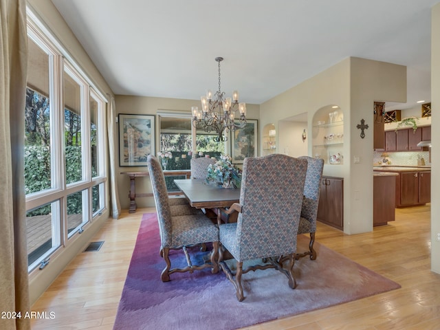 dining space featuring light wood-type flooring and an inviting chandelier