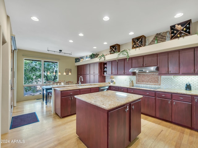 kitchen featuring black electric stovetop, a center island, light hardwood / wood-style floors, and tasteful backsplash