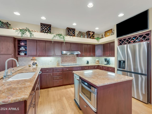 kitchen featuring sink, a kitchen island, light hardwood / wood-style flooring, appliances with stainless steel finishes, and light stone countertops