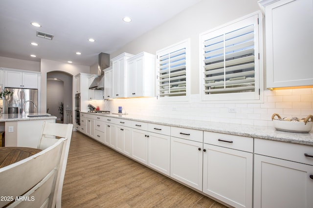 3118 E Gary Way, Phoenix, AZ 85042 - kitchen featuring appliances with stainless steel finishes, decorative backsplash, white cabinets, light wood-style flooring, and healthy amount of natural light