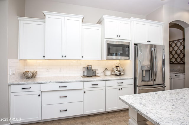3118 E Gary Way, Phoenix, AZ 85042 - kitchen with stainless steel appliances, arched walkways, white cabinets, decorative backsplash, and light wood finished floors