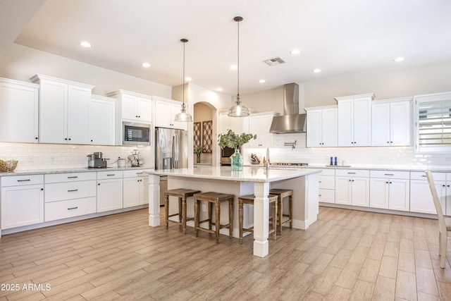 3118 E Gary Way, Phoenix, AZ 85042 - kitchen with wall chimney exhaust hood, stainless steel appliances, backsplash, an island with sink, and a kitchen breakfast bar