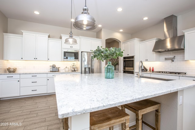 3118 E Gary Way, Phoenix, AZ 85042 - kitchen with wall chimney range hood, appliances with stainless steel finishes, a large island with sink, decorative backsplash, and white cabinetry