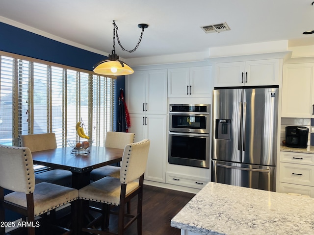 kitchen with dark wood-style flooring, visible vents, appliances with stainless steel finishes, white cabinets, and light stone countertops