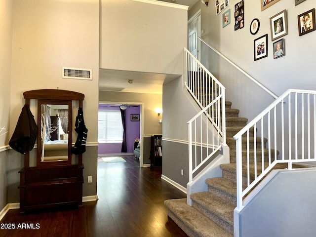 stairway with hardwood / wood-style flooring, visible vents, and baseboards