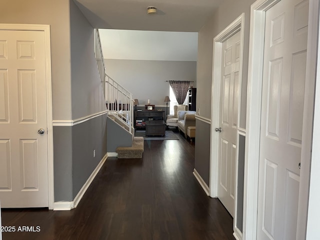 hallway with stairs, dark wood-style flooring, and baseboards