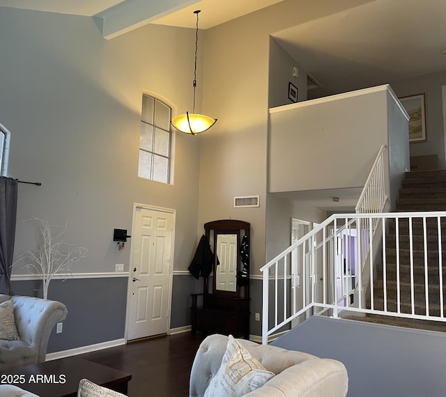 foyer with stairs, visible vents, wood finished floors, and a towering ceiling