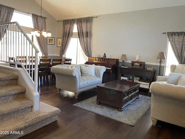 living area with a chandelier, dark wood finished floors, vaulted ceiling, and stairs