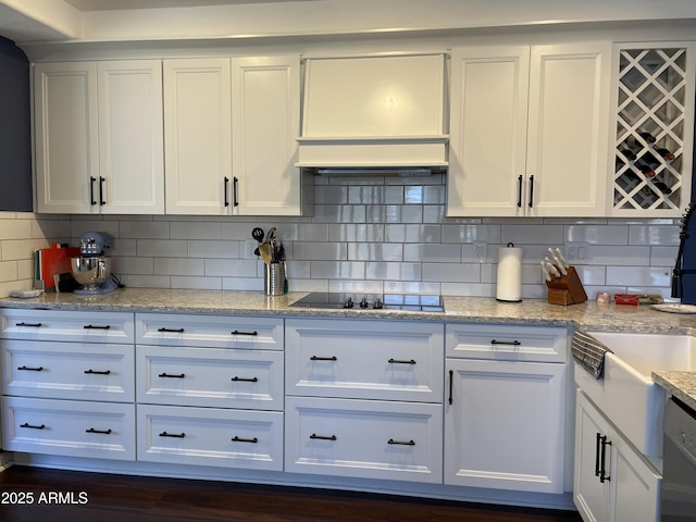 kitchen featuring black electric cooktop, premium range hood, stainless steel dishwasher, and white cabinetry