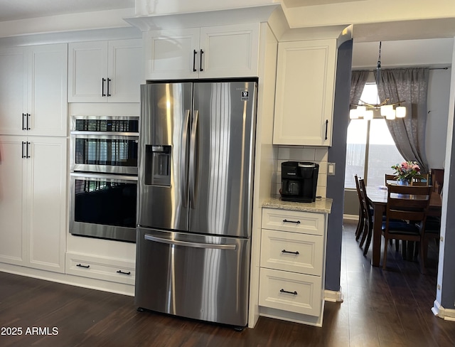 kitchen featuring light stone counters, dark wood finished floors, stainless steel appliances, white cabinetry, and a chandelier