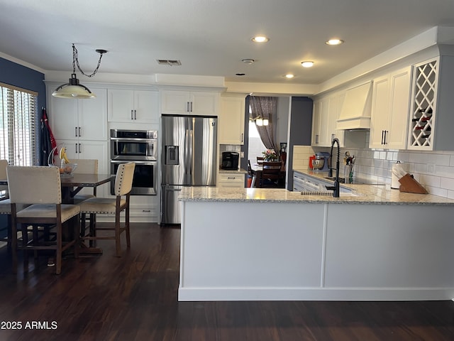 kitchen with stainless steel appliances, light stone counters, backsplash, and custom range hood