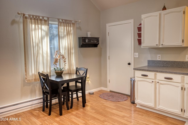 dining space featuring a healthy amount of sunlight, lofted ceiling, light hardwood / wood-style floors, and baseboard heating