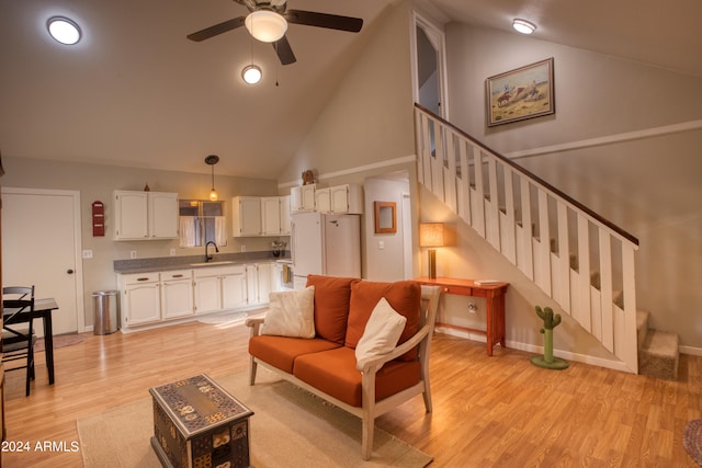 living room with high vaulted ceiling, ceiling fan, light hardwood / wood-style floors, and sink