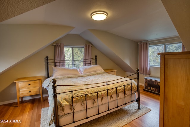 bedroom with lofted ceiling and light wood-type flooring