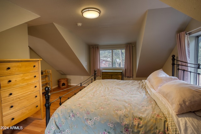 bedroom with light hardwood / wood-style floors and lofted ceiling