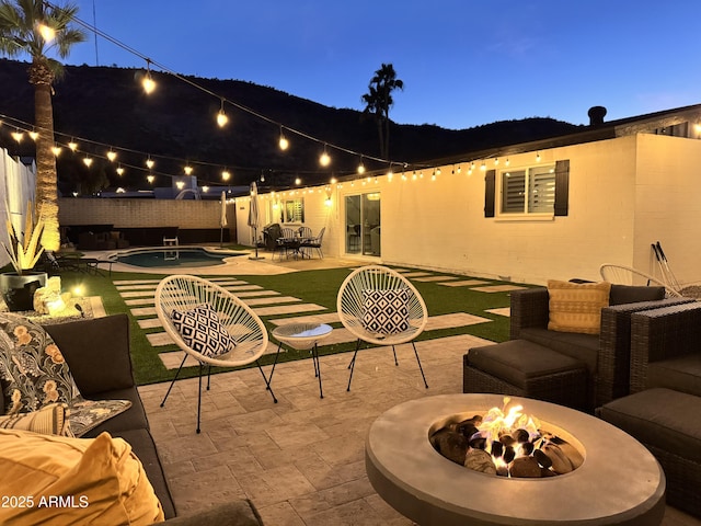 patio terrace at dusk featuring a fenced in pool and an outdoor fire pit