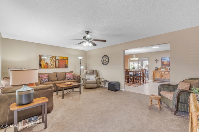 living room with light carpet, a textured ceiling, light tile patterned flooring, and ceiling fan with notable chandelier