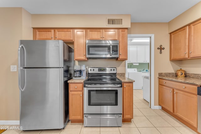 kitchen with light tile patterned floors, light stone countertops, visible vents, appliances with stainless steel finishes, and washer and clothes dryer