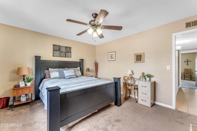 carpeted bedroom with ceiling fan, baseboards, visible vents, and a textured ceiling