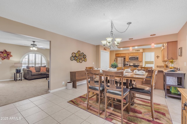 dining room with baseboards, light carpet, ceiling fan with notable chandelier, light tile patterned flooring, and a textured ceiling