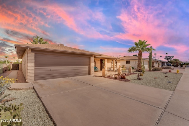 ranch-style home with brick siding, an attached garage, concrete driveway, and fence