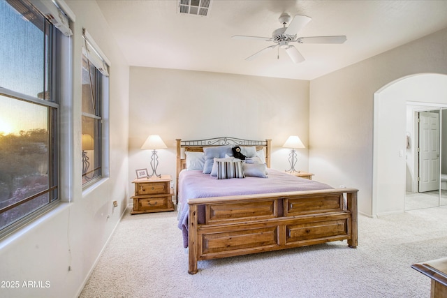 bedroom featuring ceiling fan, multiple windows, and light carpet