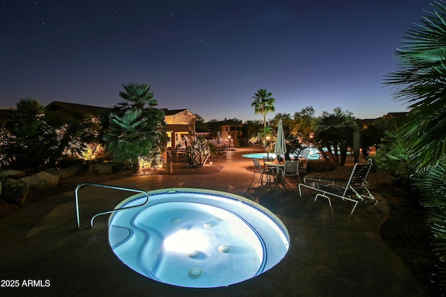 pool at dusk featuring a community hot tub and a patio area