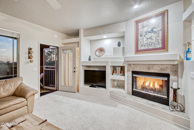 living room featuring built in features, carpet, and a tile fireplace