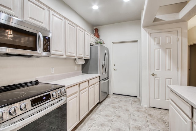 kitchen featuring light tile patterned flooring, appliances with stainless steel finishes, and white cabinets