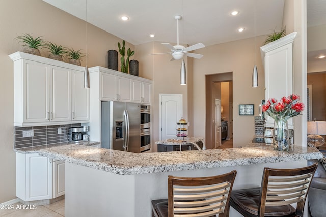 kitchen featuring tasteful backsplash, a kitchen breakfast bar, kitchen peninsula, stainless steel fridge with ice dispenser, and white cabinetry