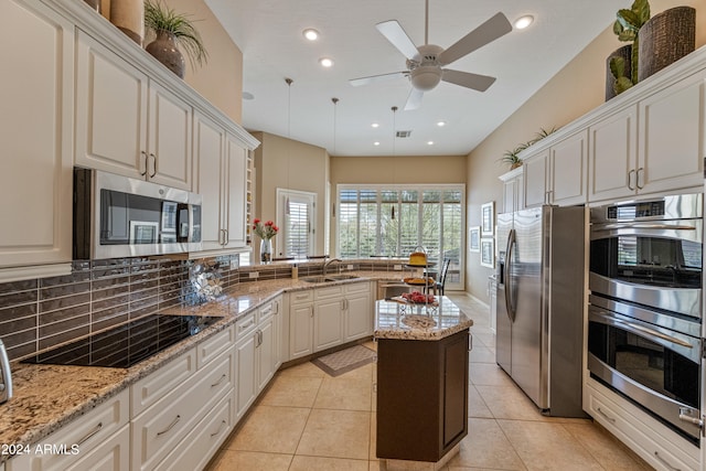 kitchen with stainless steel appliances, light stone countertops, and white cabinetry