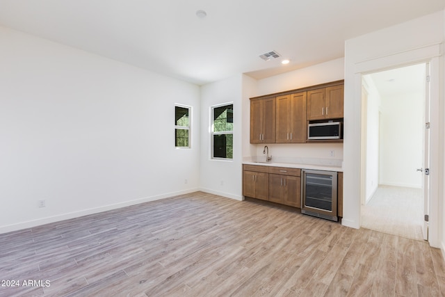 kitchen featuring light wood-type flooring, beverage cooler, and sink