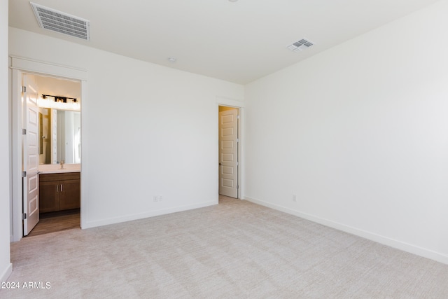 unfurnished bedroom featuring light colored carpet and connected bathroom