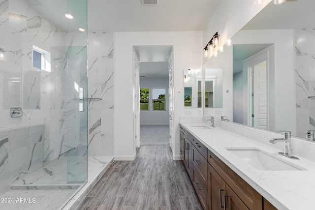 bathroom with tiled shower, vanity, a healthy amount of sunlight, and hardwood / wood-style flooring