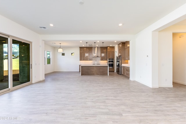 unfurnished living room with sink and light hardwood / wood-style floors