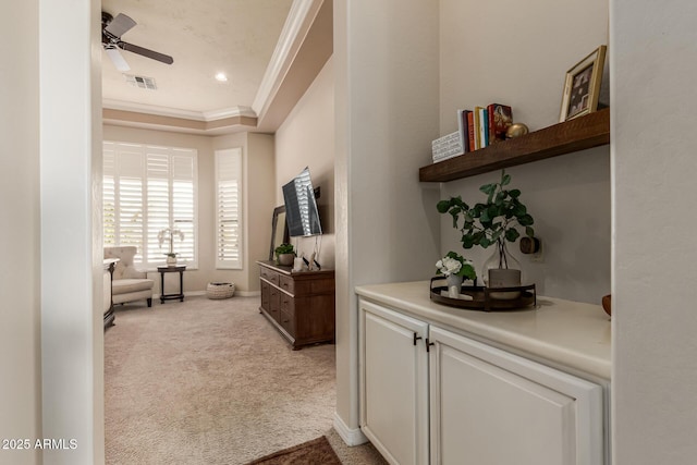 interior space with crown molding, light colored carpet, and a tray ceiling