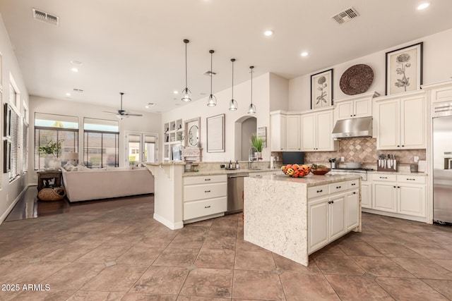 kitchen featuring light stone counters, decorative light fixtures, a center island, kitchen peninsula, and stainless steel appliances