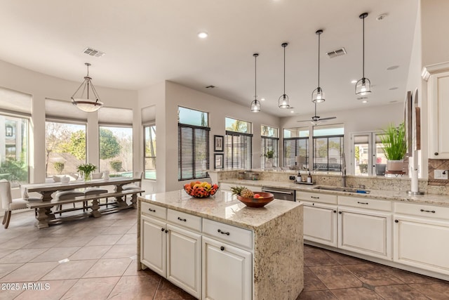 kitchen featuring stainless steel dishwasher, decorative light fixtures, sink, and a wealth of natural light