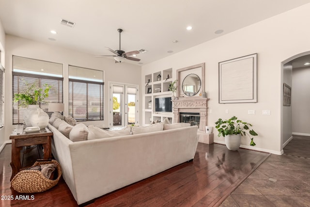 living room with dark hardwood / wood-style flooring, built in features, and ceiling fan