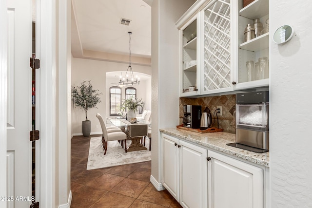 bar featuring decorative light fixtures, white cabinetry, dark tile patterned flooring, decorative backsplash, and a raised ceiling