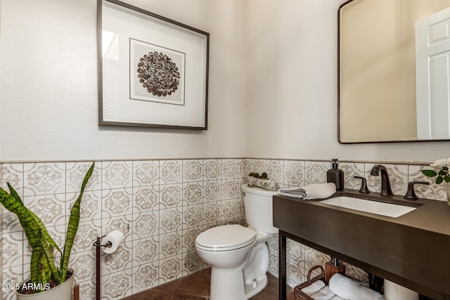 bathroom with tile patterned floors, toilet, sink, and tile walls