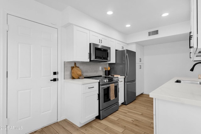 kitchen featuring decorative backsplash, sink, white cabinets, and appliances with stainless steel finishes