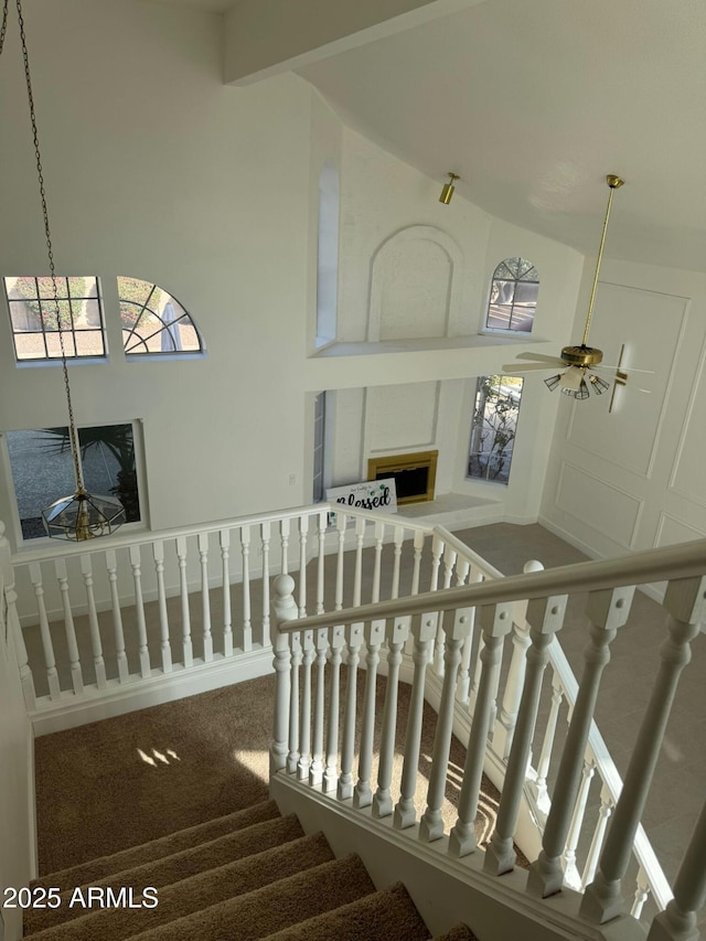 stairway featuring ceiling fan, carpet flooring, and a high ceiling