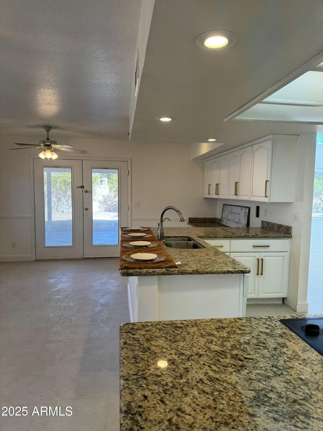 kitchen featuring sink, white cabinetry, a textured ceiling, ceiling fan, and dark stone counters