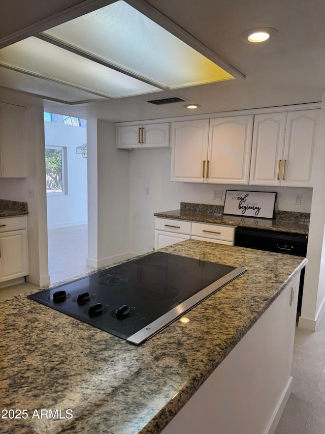 kitchen with white cabinetry, black electric stovetop, light tile patterned flooring, and dark stone countertops