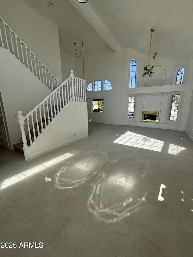 unfurnished living room featuring beamed ceiling and a high ceiling