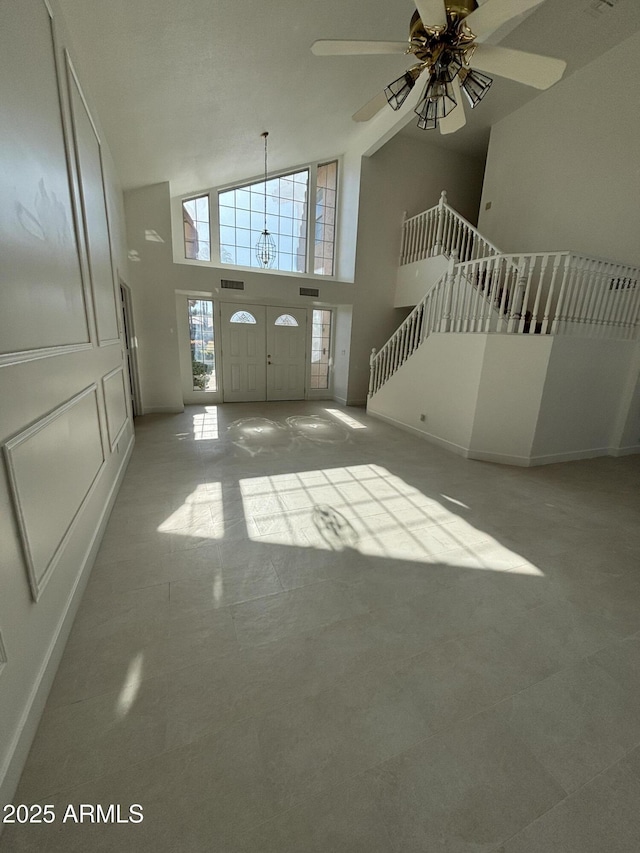 foyer entrance featuring ceiling fan and high vaulted ceiling