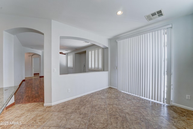 unfurnished room featuring recessed lighting, visible vents, arched walkways, and baseboards