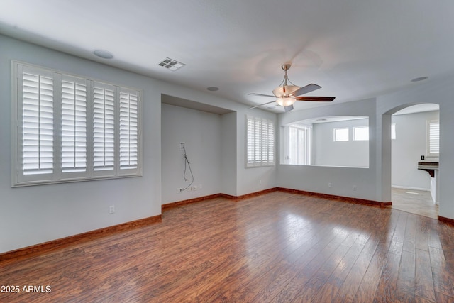 spare room with a ceiling fan, baseboards, visible vents, arched walkways, and hardwood / wood-style flooring